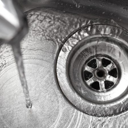 Stainless steel sink plug hole close up with water